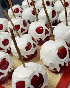 there are many red and white desserts on the table with toothpicks in them