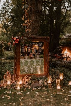 an outdoor ceremony with candles and a large mirror on the ground in front of it