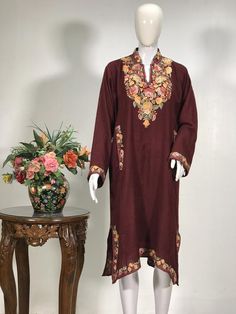 A stunningly marvellous Pheran. This Pheran features intricate Kashmir Aari embroidery on neckline and sleeves.- - - - - - - - - - - - - - - - - - - - Product Details- Condition: Brand New (made to order)- Style: Pheran Tunic with Half Band Collar- Fabric: Pure Wool- Colour: Wine- Embroidery: Aari Work- Embroidery Colour: Multi-Colour- Standard Length: 40" - Care Instructions: Dry Clean Only.**If you want the Tunic to be shorter or longer, just send us a message, and we will tailor it accordingl Pheran Designs, Kashmiri Phiran, Kashmiri Kurta, Kashmiri Dress, Kashmiri Pheran, Wine Embroidery, Kashmiri Suits, Kashmiri Work, Yellow Kurti