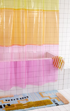 a colorful bathroom with pink, yellow, and orange shower curtains