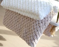 a knitted blanket sitting on top of a wooden floor next to a vase with flowers