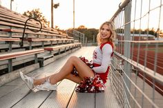 a cheerleader sitting on the bleachers at a football game in her red and white outfit