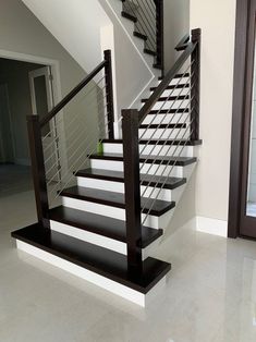 a white and black stair case in a house with tile flooring on the ground