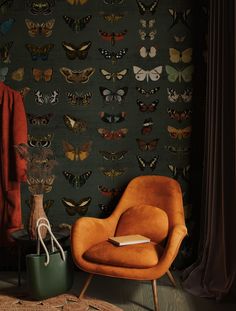 an orange chair sitting in front of a wall with butterflies on it and a book