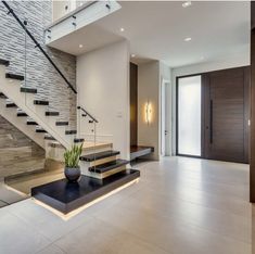 a modern entryway with stairs and plant in the center, surrounded by stone walls