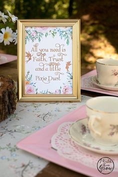 a table topped with plates and cups next to a framed sign that says, all you need is love