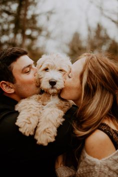 a man kissing a woman while holding a dog in his lap and kissing her on the cheek