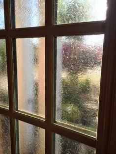 a window that has some frost on the glass and it looks like rain is coming down