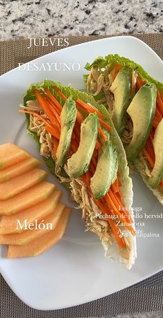 a white plate topped with lettuce and carrots next to sliced avocado