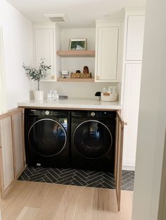 a washer and dryer in a small room with white cupboards on the wall