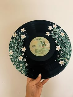 a hand holding up a black record with white flowers on it