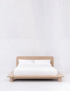 a bed sitting on top of a wooden platform next to a white wall and floor