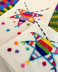 three colorful embroidered napkins sitting on top of each other with different designs and colors