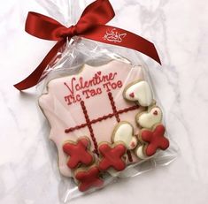 a decorated cookie in the shape of a cross and teddy bears with a red ribbon tied around it