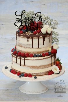 a three layer cake with berries, strawberries and chocolate frosting that says love is sweet