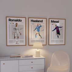 two soccer posters hang on the wall above a white dresser and side table with a lamp