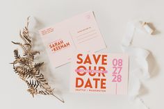 two pink and orange save the dates cards on top of each other next to a plant