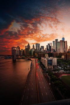 the city skyline is lit up at sunset with birds flying in the sky over it