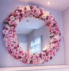 a mirror that has flowers on it in front of a white mantle with candles and lights