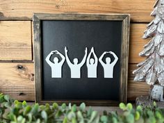 some paper cutouts are hanging on a wooden wall next to a christmas tree and potted plant