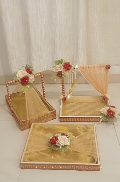 three gold trays with red and white flowers on them are sitting on the floor