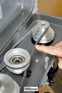 a person is holding the pulley wheel on top of an appliance that's open