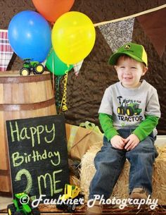 a young boy sitting on top of hay next to balloons and a sign that says happy birthday me