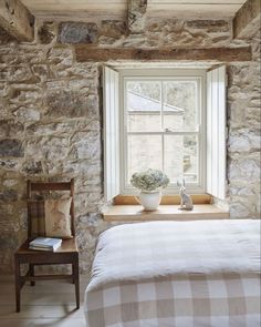 a bed sitting under a window next to a wooden table with a potted plant on it