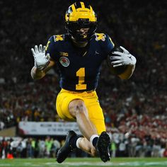 a football player is running with the ball in his hand and wearing a yellow uniform