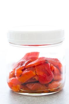 a glass jar filled with sliced fruit on top of a table