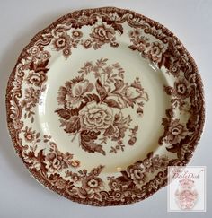 a brown and white plate with flowers on it's rim, sitting on a table