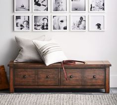 a wooden bench sitting in front of a wall with pictures on the wall above it