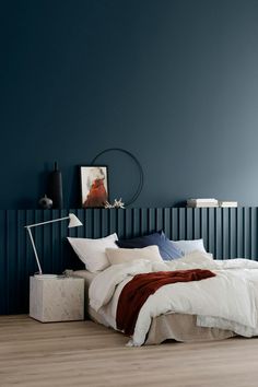 a bedroom with blue walls and white bedding