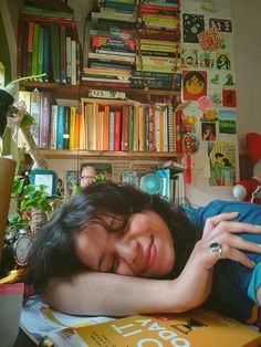 a woman laying on top of a table next to a book shelf filled with books