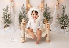 a baby is sitting on a chair in front of some christmas trees and snowflakes