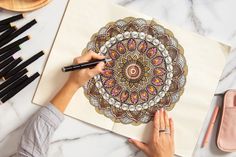 a woman is drawing on paper with colored pencils