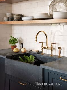 a kitchen sink with two faucets on the side and an open shelf above it