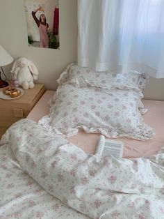 an unmade bed with pink and white flowers on it