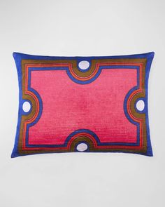 a pink and blue pillow with circles on the border, in front of a white background