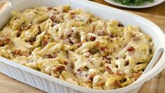 a casserole dish with meat and cheese in it on a wooden table next to plates