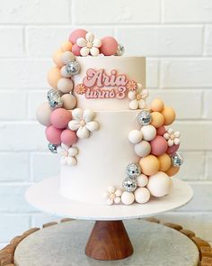 a three tiered white cake topped with lots of balloons