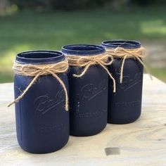 three blue mason jars tied with twine and sitting on a piece of wood outside