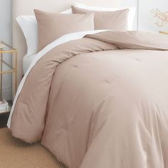 a bed with beige sheets and pillows in a bedroom