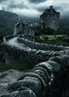 an old castle sits on top of a hill under a cloudy sky with dark clouds