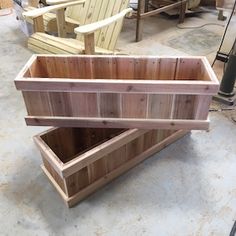 two wooden boxes sitting next to each other on top of a cement floor with chairs in the background