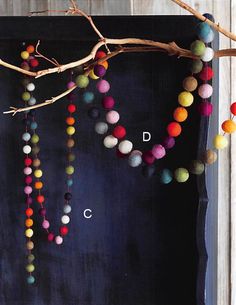 the colorful beads are hanging from the tree branch in front of the black board, which is painted blue