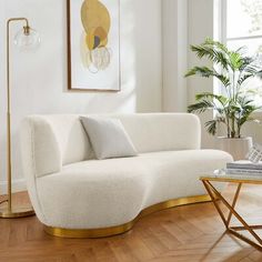 a living room with a white couch and gold accents on the floor, next to a large window