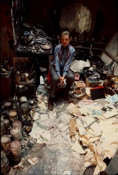 a man sitting on top of a chair surrounded by lots of papers and other items