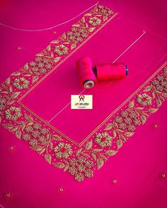 two spools of thread sitting on top of a pink cloth with gold designs