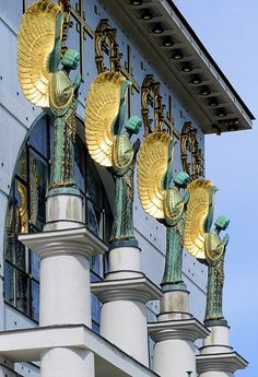 gold and green sculptures on the side of a building with blue skies in the background